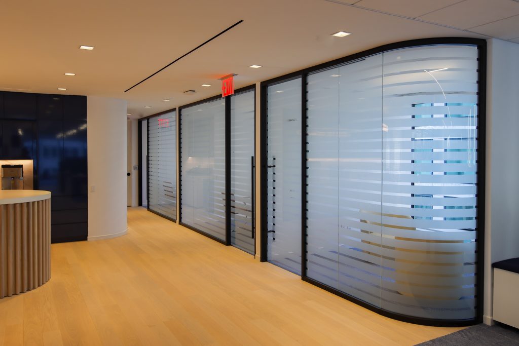 Curved glass with custom privacy film in MetroWall glass wall system.